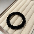 Macro shot of faceted black crystal beads on a flexible elastic hair tie in jewelry tray - Black