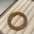 Detailed macro view of champagne beaded crystal hair tie in beige velvet jewelry box - Champagne