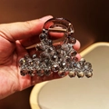 Detail view of a luxury shark hair clip with grey crystal beads and golden spring - Gray