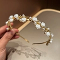 Dettaglio del cerchietto dorato con rose in resina, perle e strass su uno sfondo caldo - Stile Rosa Bianca / Bianco Sporco