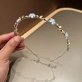 Dettaglio del cerchietto in metallo dorato con fiori blu, perle e strass lucenti - Blu
