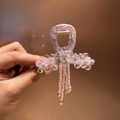 Dettaglio della molletta per capelli in tessuto viola con perline e nappe eleganti - Rosa
