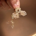 Dettaglio di un fermaglio a fiocco color oro con cristalli e nappine pendenti - Rosa