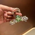 Detail of green crystal and pearl hair claw clip with golden metal spring structure - Colorful