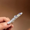 Elegante fermaglio per capelli argento con strass verdi e perle su uno sfondo marrone - Stile Zirconia