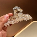 Primer plano de pinza para el cabello color champán con cristales brillantes en mano - Rosa