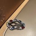 Macro shot of silver snap clip with colorful rhinestones on a warm gold background - Cloud Multicolor