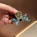 Dettaglio macro della molletta a farfalla con cristalli blu e manico in seta verde - Verde