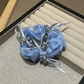 Détail d'un chouchou bleu clair avec perles de cristal sur un plateau en velours - Bleu