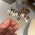 Primer plano de un peine de pelo dorado con perlas y cristales sujeto en la mano - Gris