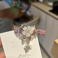 Dettaglio del fermaglio floreale con cristalli iridescenti e base lavanda - Viola