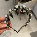 Detail view of crystal headband featuring white 3D flowers and sparkling beaded texture - Black