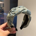 Detail eines blauen Denim-Stirnbands mit goldenen Sternen und silbernen Nieten - Hellblaues Denim