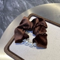 Vista dettagliata di uno scrunchie di velluto marrone con trama a righe e tre perle - Marrone
