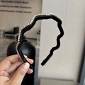 Dettaglio di un cerchietto ondulato in velluto nero con perle finte decorative - Nero