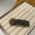 Close-up of luxury rectangular hair clip with dark grey crystals and a champagne beaded flower - Gray (B82-104)