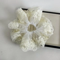 Detail van witte kanten scrunchie met delicate crèmekleurige parels en geborduurde bloemen - Beige