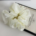 Oversized ivory scrunchie made of shiny organza fabric on a wooden jewelry display tray - Off-white