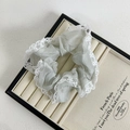 Detail van wit kant op de glanzende zilveren organza scrunchie op een plateau - Grijsblauw