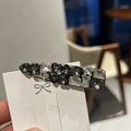 Detail einer Retro-Haarklammer mit Herz- und Sternkristallen auf einer Displaykarte - Schwarz