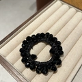 Detail of a black crystal beaded hair tie displayed in a jewelry box with multi-faceted beads - Black