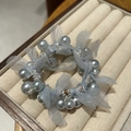 Detailed view of light blue pearl scrunchie with camellia mesh bow on a cream tray - Blue Mesh Bow
