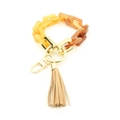 Dettaglio portachiavi a catena in acrilico ambrato con metallo dorato e nappa beige - Ambra Sfumata e Nappina Beige
