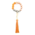 Beaded keychain bracelet with orange tassels and patterned wood beads on white background - Orange