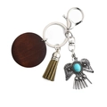 Close-up of Bohemian eagle keychain with wood pendant, leather tassel and turquoise stone - Army Green