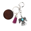 Vintage bohemian eagle keychain with purple tassel and wood disc on white background - Purple