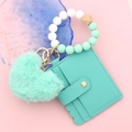 Detail of mint green leather wallet with plush heart charm and silicone bead keychain - Green