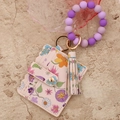 Close-up of pink floral card holder with beaded wristlet and leather tassel keychain - Purple Flower