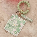 Tarjetero con estampado floral, cuentas de silicona verde menta y borla de cuero - Verde Pálido