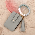Flat lay of a grey leather card wallet with a silicone bead wristlet and tassel charm - Gray
