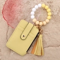 Macro view of bright yellow pebble leather wallet with silicone bead bracelet and gold clasp - Yellow
