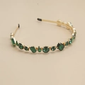 Détail d'un serre-tête doré orné de strass vert émeraude de formes et tailles variées - Strass Vert