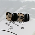 Dettaglio di un fermaglio in resina tartarugata e nera su elegante raso bianco - Leopardo Chiaro