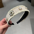 Vue détaillée d'un serre-tête en tweed avec perles et fleur de camélia en main - Blanc Cassé