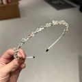 Close-up of sparkling crystal and rhinestone embellishments on a silver metal headband - Clear White