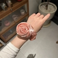 Chouchou rose en satin avec fleur de rose montrant la texture soyeuse sur le poignet - Rose