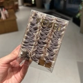 Gros plan de chouchous violets en tissu plissé dans une boîte cadeau élégante - Gris en Boîte