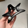 Detail of matte black star hair claw clip with a pearl accent held in hand for size - 10.3cm / Black Pearl Style