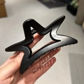 Detailed close-up of a matte black star-shaped hair claw clip held in hand - 10.3cm / Black Smooth