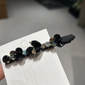 Detail van handgemaakte bloemen haarspeld met zwarte strass en gouden accenten - Zwart