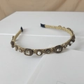 Close-up of gold headband with woven metal patterns, white pearls and grey crystals - Clear Oval Gemstone