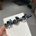 Gedetailleerde opname van handgemaakte donkerblauwe kristallen haarclip op witte kaart - Blauw
