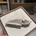 Detail of elegant champagne satin hair claw with white pearls on a wooden tray - Beige