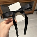 Détail d'un nœud en satin noir montrant la texture soyeuse et brillante de l'agrafe - Noir