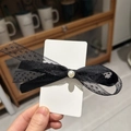 Detalle de pinza de pelo con lazo de encaje negro y perla sobre tarjeta blanca - Negro