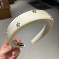 Dettaglio di un cerchietto in raso crema con strass scintillanti a forma di stella - Bianco Sporco